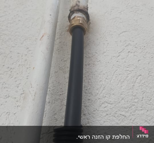 צינור שחור עם מחבר מתכת על קיר